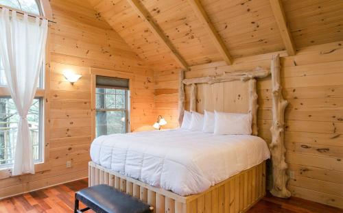 um quarto com uma cama num chalé de madeira em Whispering Pines Treehouse by Amish Country Lodging em Millersburg