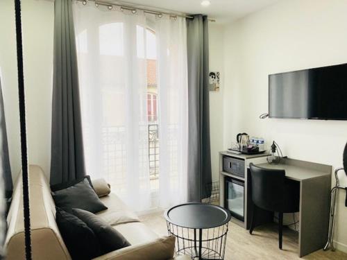 a living room with a couch and a large window at Paris Hotel in Clichy