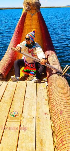 a man sitting on the end of a boat at Uros Maya Lodge in Puno