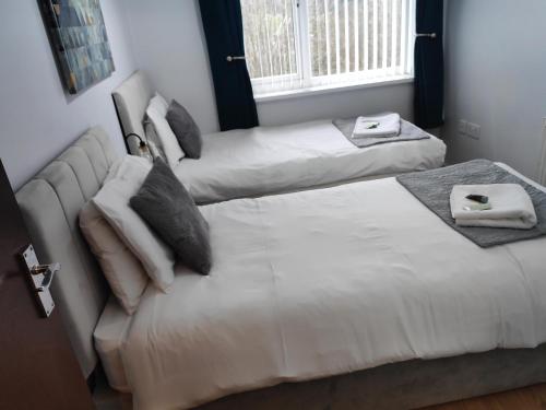 two beds in a room with white sheets and pillows at The Old Post Box in Leeds