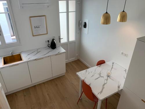 a kitchen with white cabinets and a table at Irrésistible chartreuse in Toulouse