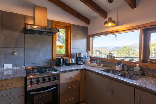 サン・マルティン・デ・ロス・アンデスにあるOliver Mountain Home Blueのキッチン(コンロ、シンク付)、窓が備わります。