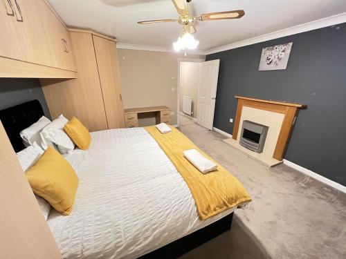 ein Schlafzimmer mit einem großen Bett mit gelber Bettwäsche und einem Kamin in der Unterkunft 4 Bed Town house with 7 beds and sleeps 8 in Kent