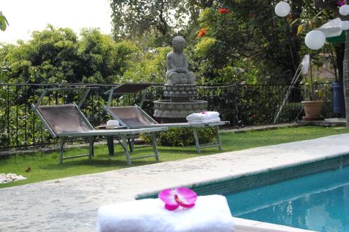 a pool with two lounge chairs and a statue next to it at Tu cabaña Cuernavaca - hospedaje by Arcadia in Cuernavaca
