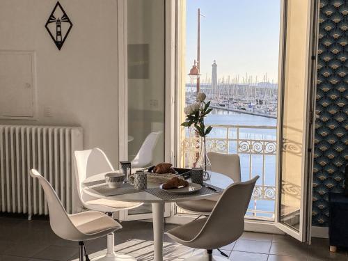een eetkamer met een tafel en stoelen en een raam bij Le Phare in Sète