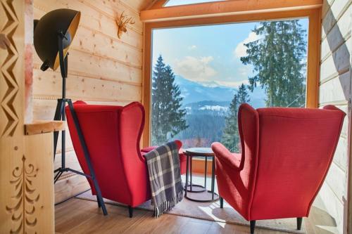 a room with two red chairs and a large window at Witkówka New Folk Luxury - Sauna & SPA x in Kościelisko