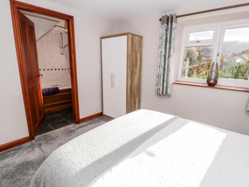 a white bedroom with a bed and a window at Peniarth in Pen-y-bont-fawr