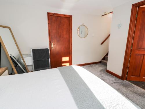 a bedroom with a white bed and a wooden door at Peniarth in Pen-y-bont-fawr