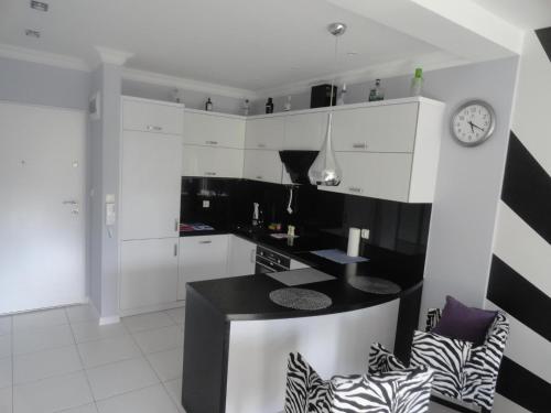 a black and white kitchen with a clock on the wall at Lukusowy apartament dla Pary in Mrągowo
