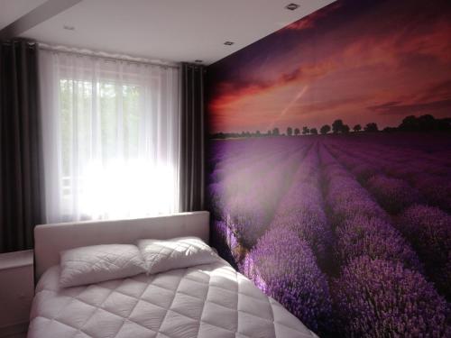 a bedroom with a lavender mural on the wall at Lukusowy apartament dla Pary in Mrągowo