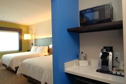 Holiday Inn Express & Suites Onalaska - La Crosse Area, an IHG Hotel في Onalaska: غرفة في الفندق بها سرير وتلفزيون على الحائط