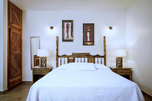 1 dormitorio con 1 cama blanca y 2 mesitas de noche en Beach House Condos, Negril en Negril