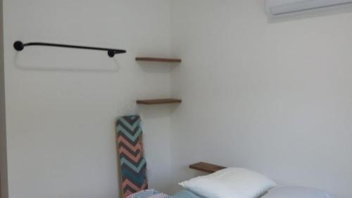 a bedroom with a bed and shelves on the wall at Casa geminada 2 no Mariscal in Bombinhas