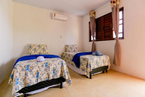 a bedroom with two beds and a window at Casa aconchegante em São Miguel dos Milagres-AL in São Miguel dos Milagres