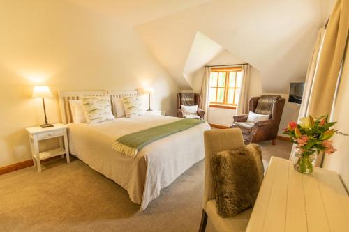 a bedroom with a large bed and two chairs at Wanaka Homestead Lodge & Cottages in Wanaka