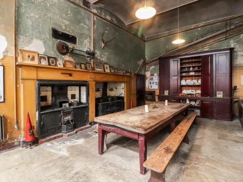 ein großer Raum mit einem Holztisch und einem Ofen in der Unterkunft Cook's Flat in Wrexham