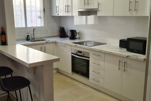 埃斯特波納的住宿－Estepona port beachside apartment - Marina Bay，厨房配有白色橱柜、水槽和微波炉