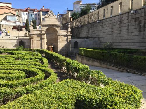 an ornamental garden with hedges and a wall at Joya en Orense Centro in Ourense