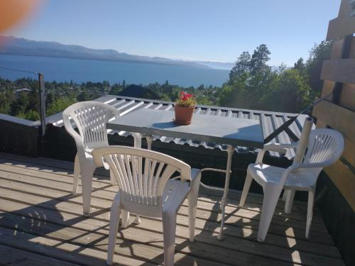 a table and chairs on a deck with a view of the water at DECKS AL LAGO in San Carlos de Bariloche