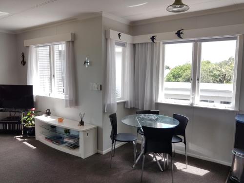 a living room with a table and chairs and windows at Coromandel Tapu - Beachfront Escape in Tapu