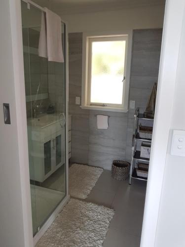 a bathroom with a shower and a sink and a window at Coromandel Tapu - Beachfront Escape in Tapu