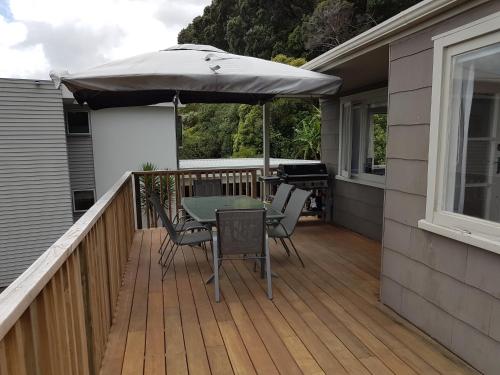 a wooden deck with a table and an umbrella at Coromandel Tapu - Beachfront Escape in Tapu