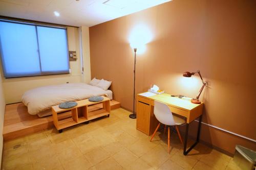 a bedroom with a bed and a desk with a lamp at La Union ラウニオン in Fukushima