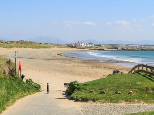 a sandy beach next to the ocean with houses in the background at Trewan Chalet in Holyhead