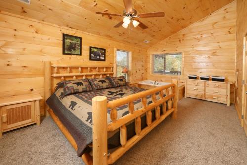 una camera da letto in stile baita di tronchi con letto e ventilatore a soffitto di Deer Pass Lodge a Pigeon Forge
