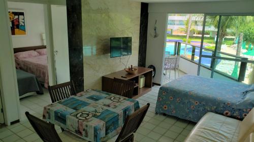 Ancorar Resort Vista Mar Flat 6103 في بورتو دي غالينهاس: غرفة نوم مع طاولة وسرير وشرفة
