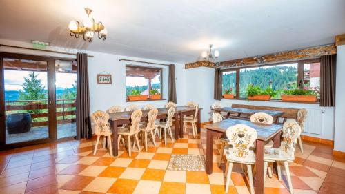 uma sala de jantar com mesa, cadeiras e janelas em Vila Stefana Paltinis em Păltiniş