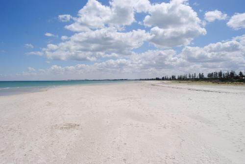 a beach with white sand and clouds in the sky at Port Adelaide Backpackers in Adelaide