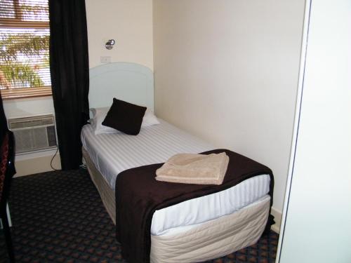 a small room with a bed with a mirror at Grand Tasman Hotel in Port Lincoln