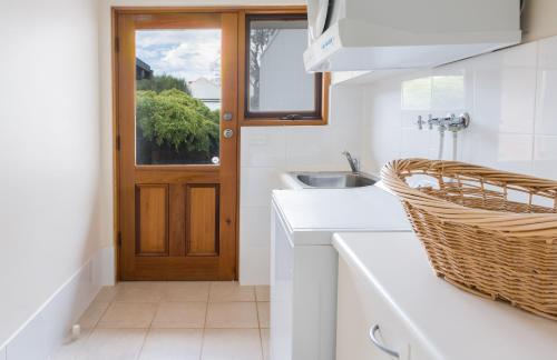a white kitchen with a sink and a door at Baudin House in Penneshaw