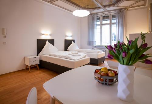 Aparthotel Villa Elon في فورث: غرفة مع سرير وطاولة مع وعاء من الفواكه