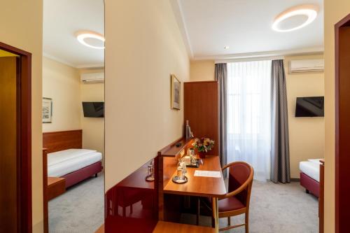 a hotel room with a desk and a bedroom at Austria Classic Hotel Wien in Vienna
