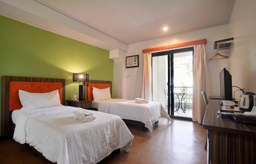 una camera d'albergo con due letti e una televisione di Momarco Forest Cove a Tanay