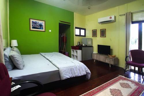 a bedroom with a bed and a green wall at Laman Sakinah Merlimau in Merlimau