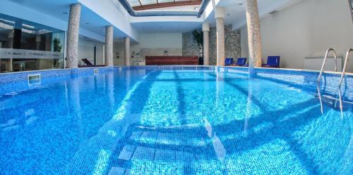 a large blue swimming pool in a building at 50m from Ski Piste 1 BR Apartment in Predela 2 in Bansko