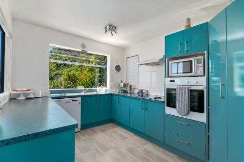 a kitchen with blue cabinets and a window at Ocean Spa Views in Nelson