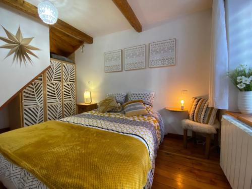 een slaapkamer met een bed met een gele deken bij Duplex cosy au cœur de Barcelonnette in Barcelonnette