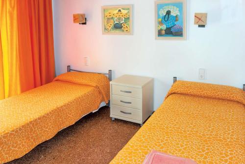 カラン・ポルテルにあるChiquitaのベッドルーム1室(オレンジのシーツとドレッサー付きのベッド2台付)
