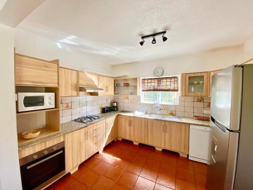 a large kitchen with wooden cabinets and a refrigerator at Beachfront Villa in a beautiful and secured complex in Flic-en-Flac