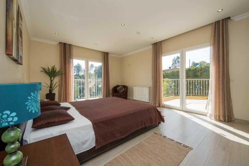 a bedroom with a large bed and large windows at Casa das Oliveiras - OLIVE TREE in Monchique