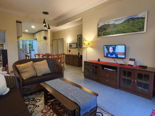 sala de estar con sofá y TV de pantalla plana en Gerard's Place Nature Heaven Apartment en Tanah Rata