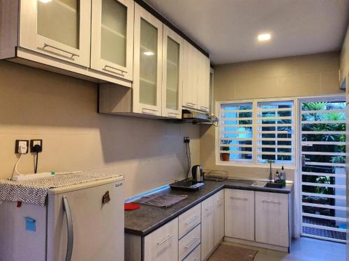cocina con armarios blancos y nevera blanca en Gerard's Place Nature Heaven Apartment en Tanah Rata