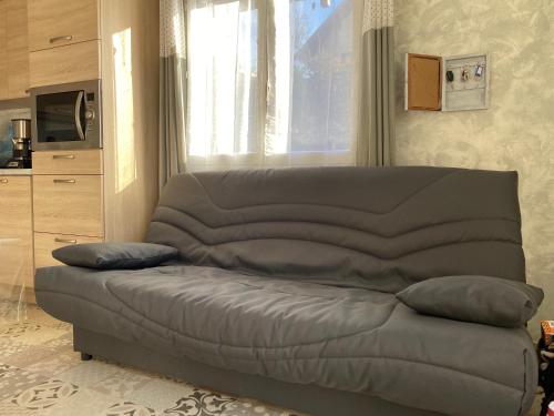 un sofá en una sala de estar con ventana en Embrun - Appartement 4/6 personnes avec extérieurs en Embrun