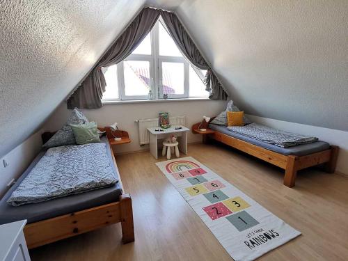 a attic room with two beds and a window at Haus Wyden in Utersum