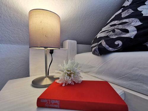 a table with a lamp and a red book on a bed at Haus Wyden in Utersum