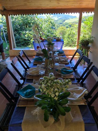 a long table with chairs and plates and flowers on it at Sítio Colibri - Serra da Mantiqueira in Brazópolis